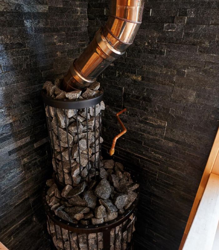 Conduit de poêle en cuivre – Ramonage et entretien Poêle à bois avec conduit en cuivre et pierres volcaniques pour le chauffage, nécessitant un ramonage régulier.