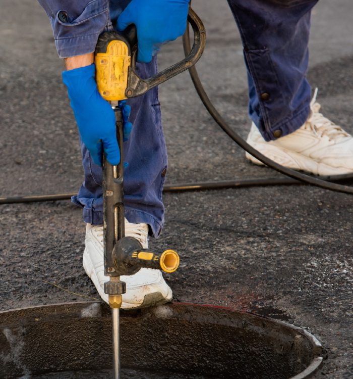 Nettoyage haute pression – Hydrocurage C9 Services Technicien effectuant un hydrocurage de canalisation avec jet haute pression